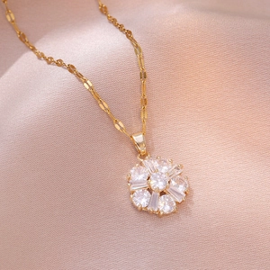 Elegante collana con ciondolo a girasole dorato e zirconi su sfondo di seta champagne