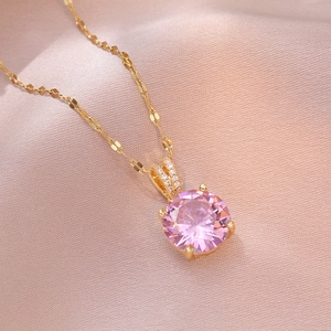 Collier en acier doré avec pendentif en zircon rose posé sur un tissu en satin rose élégant
