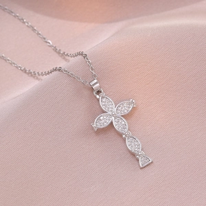 Elegant silver cross pendant necklace with sparkling cubic zirconia on silk background
