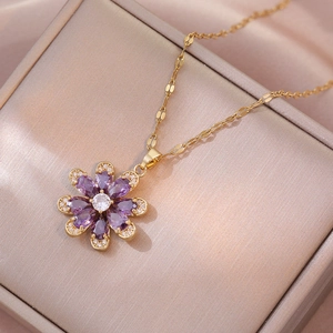 Gold flower pendant necklace with purple zircon petals and crystal center on display box