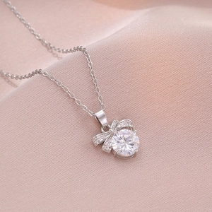 Collier à pendentif nœud en argent avec pierres étincelantes sur soie rose