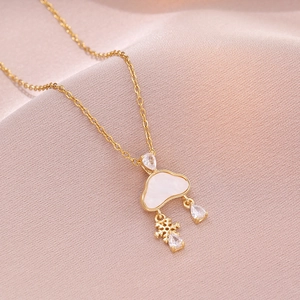 Gold cloud necklace with white shell pendant, snowflake and zircon raindrops on silk background