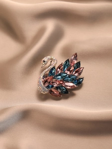 Détail de broche cygne aux zircons bleus sur fond de soie couleur champagne