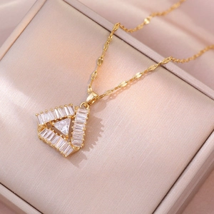 Elegant gold geometric triangle pendant necklace with cubic zirconia on jewelry box