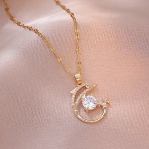 Elegant gold dolphin pendant necklace with white zircon on pink satin background