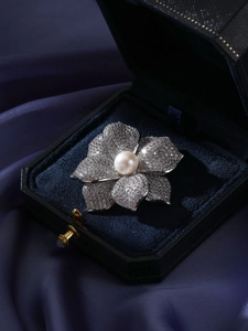 Vue macro d'une broche fleur avec perle d'eau douce et zircons sur velours bleu