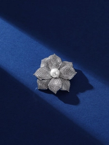 Détail macro d'une broche fleur 3D sertie de cristaux et une perle d'eau douce centrale