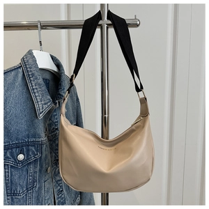 Detail of beige crescent crossbody bag featuring FASHION & BAGS text and nylon strap