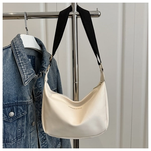 Detail of cream white leather bag with textured finish and black gold fabric strap