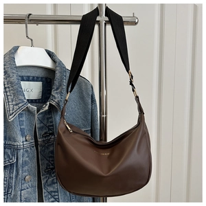 Macro detail of brown PU leather dumpling bag with adjustable wide strap and gold text