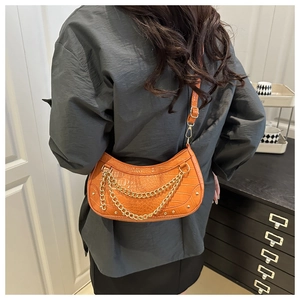 Détails du cuir croco orange sur le sac croissant avec chaînes dorées et rivets