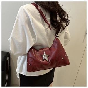 Détail du sac bandoulière bordeaux avec grande boucle étoile argentée et clous latéraux