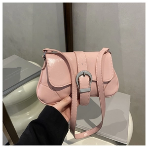 Close-up of pink glossy leather saddle bag with silver horseshoe buckle and flap closure