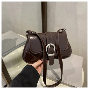 Detail view of a vintage dark brown patent leather underarm bag with silver buckle