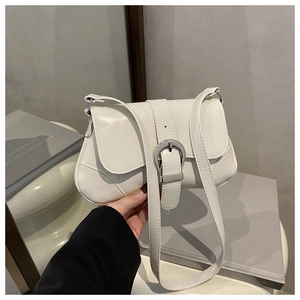 Detailed close-up of white glossy leather handbag with silver horseshoe buckle detail