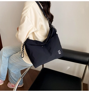 Detail of black nylon crossbody bag featuring a stylish woven strap and logo on model