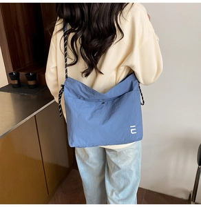 Grand sac cabas bleu en nylon avec bandoulière tissée porté dans un cadre décontracté