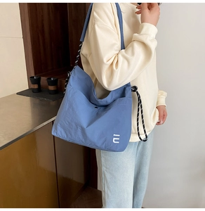 Détail du sac cabas bleu en nylon avec cordon de serrage et bandoulière à motif tissé