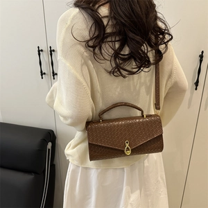Brown woven texture crossbody bag with gold ring buckle shown on a female model