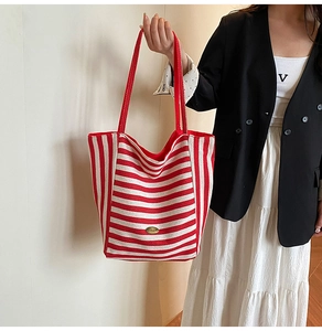 Detail of red and white striped canvas tote bag with metal logo and sturdy handles