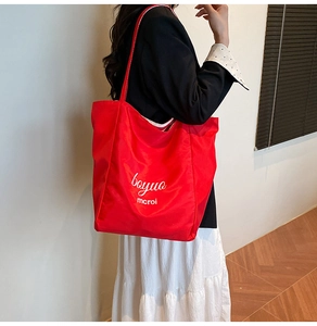 Detail view of a lightweight red nylon tote bag featuring white graphic lettering print