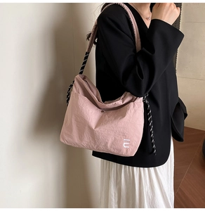 Pink nylon crossbody bag detail with striped strap and embroidered IU logo on texture