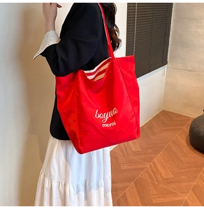 Close-up of red large capacity tote bag featuring white script lettering for daily commute