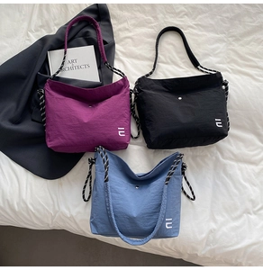 Détail des sacs cabas en nylon violet, noir et bleu avec des anses en corde épaisse