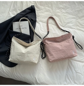 Détail du sac bandoulière en nylon avec sangle corde et broderie sur literie