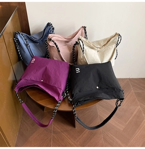 Group display of colorful nylon tote bags with braided straps on a wooden table