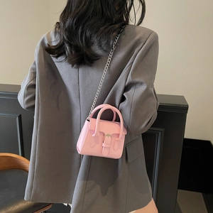 Mini pink leather handbag with silver chain strap worn over a grey blazer jacket
