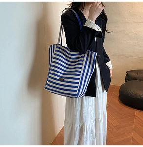 Side view of large blue and white striped canvas tote bag with wide shoulder strap