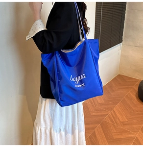 Detail of blue nylon tote bag with white lettering against a modern interior