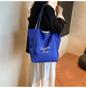 Detail of Klein blue tote bag with white straps worn by a model in a minimalist room