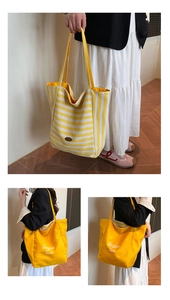 Detail of reversible striped canvas tote bag showing yellow stripes and printed lettering