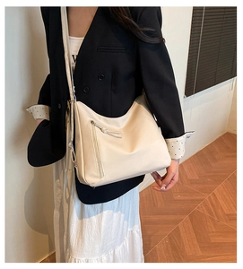 Detail of cream-white matte faux leather bag with stylish diagonal zipper and shoulder strap