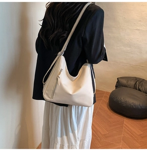 Detail of off-white hobo bag with adjustable strap shown on model in a minimalist room