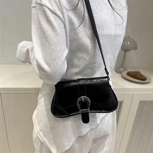 Minimalist black leather underarm bag with silver buckle worn over white outfit