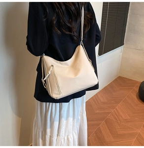Detail of cream hobo bag with fringe zipper and adjustable silver buckle on model