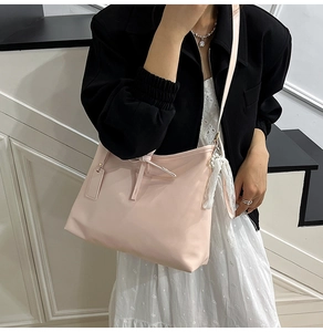 Detail of light pink hobo tote bag featuring minimalist bow and lace tassel accent