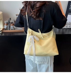 Détail du sac cabas jaune avec nœud en dentelle et pendentif perle dans un café
