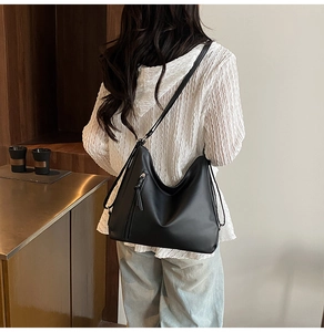 Side view of large black matte leather hobo bag with decorative long zipper detail