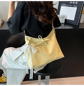 Détail d'un cabas jaune avec nœud en dentelle, pendentif perle et rubans décoratifs