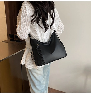 Close-up of black hobo bag with side zipper detail and adjustable strap on model
