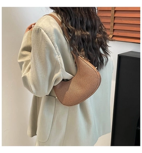 Detail of a brown crescent shoulder bag with vertical ripples worn with a gray suit