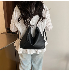 Detail view of the black matte leather hobo bag showing vertical side zipper and soft texture