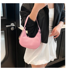 Detail of pink half-moon shoulder bag in textured leather worn under the arm
