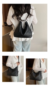 Detail view of the black leather tote showing the side zipper and tassel accents