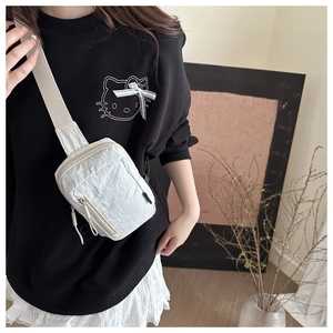 Close-up of white nylon crossbody bag with textured fabric and zipper details on model