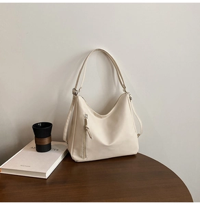 Detailed close-up of a cream white leather tote bag with a vertical zipper pocket detail